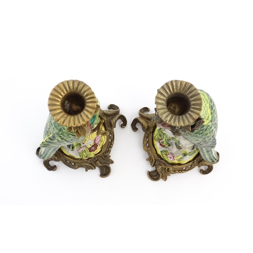 1255 - A pair of late 20thC ceramic candlesticks, the stem formed as a parrot perched on a branch with flow... 