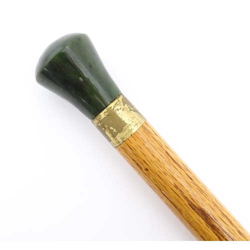 1276 - An Oriental walking stick / cane with jade coloured hardstone pommel. Approx. 38 1/4