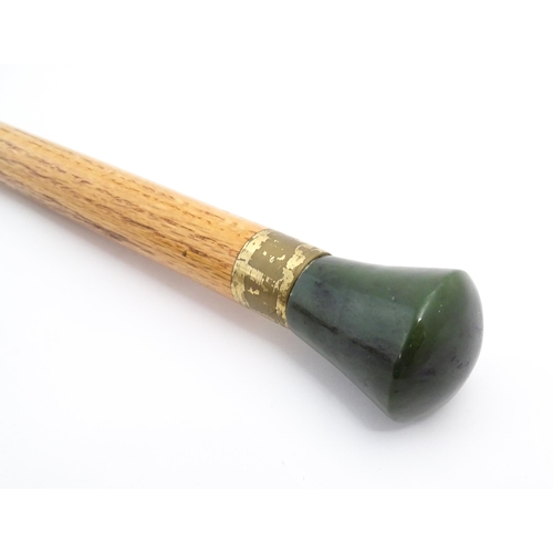 1276 - An Oriental walking stick / cane with jade coloured hardstone pommel. Approx. 38 1/4