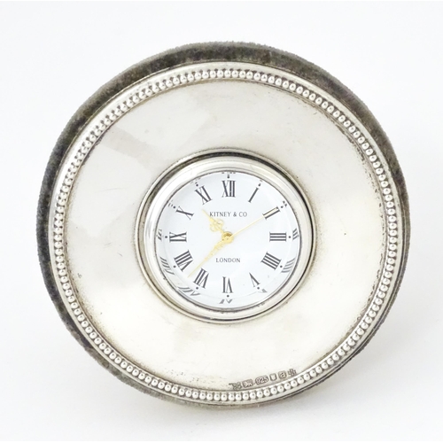 414 - A small easel back desk clock of circular form with silver surround hallmarked London 2000, maker Ki... 