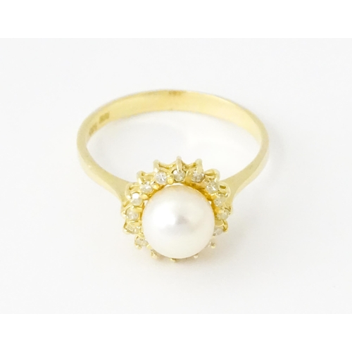 621 - A 14ct gold ring set with central pearl bordered by diamonds. Ring size approx. M