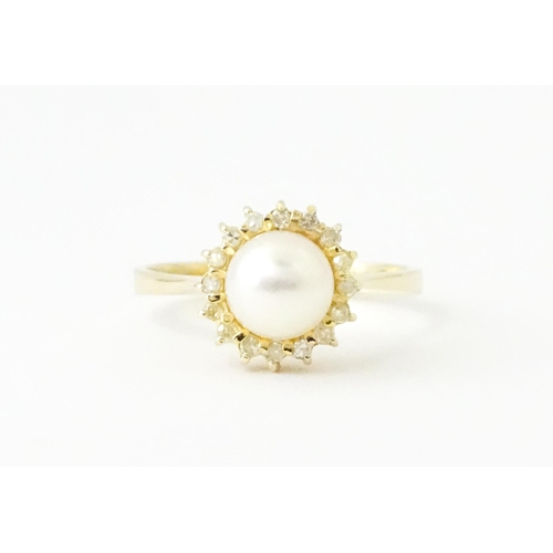 621 - A 14ct gold ring set with central pearl bordered by diamonds. Ring size approx. M