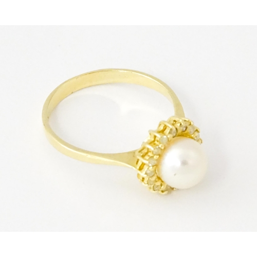 621 - A 14ct gold ring set with central pearl bordered by diamonds. Ring size approx. M