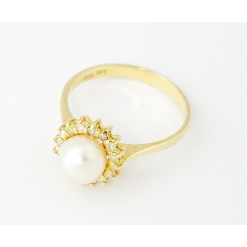 621 - A 14ct gold ring set with central pearl bordered by diamonds. Ring size approx. M