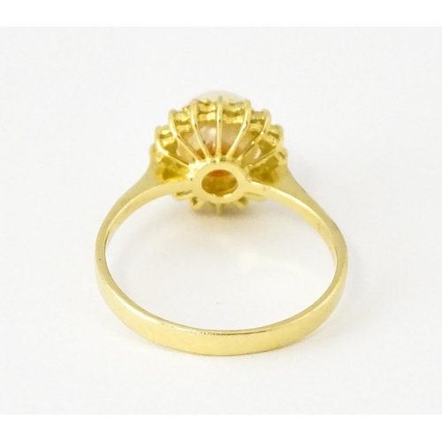 621 - A 14ct gold ring set with central pearl bordered by diamonds. Ring size approx. M