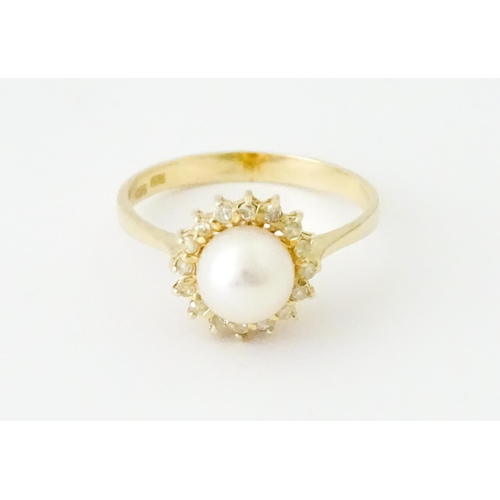 621 - A 14ct gold ring set with central pearl bordered by diamonds. Ring size approx. M