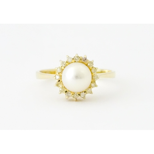 621 - A 14ct gold ring set with central pearl bordered by diamonds. Ring size approx. M