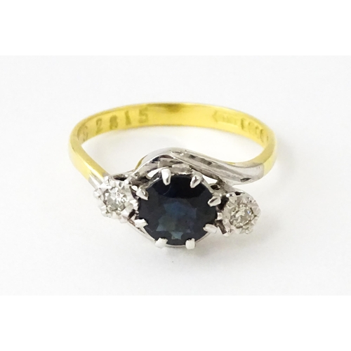 622 - An 18ct gold ring with platinum set central sapphire flanked by diamonds. Ring size approx. N