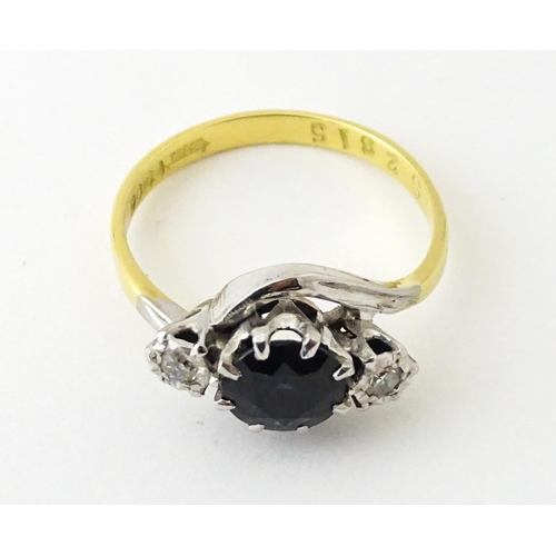 622 - An 18ct gold ring with platinum set central sapphire flanked by diamonds. Ring size approx. N