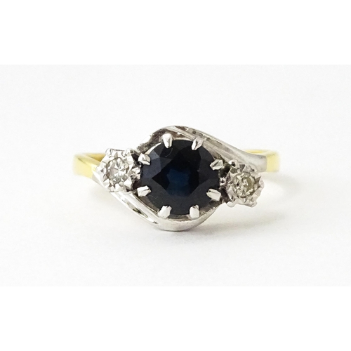 622 - An 18ct gold ring with platinum set central sapphire flanked by diamonds. Ring size approx. N