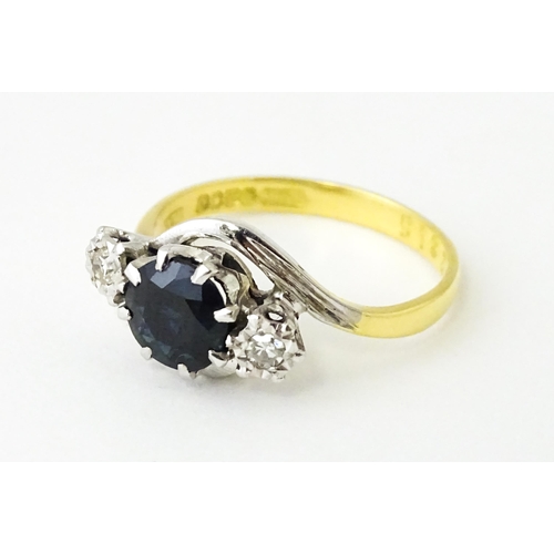 622 - An 18ct gold ring with platinum set central sapphire flanked by diamonds. Ring size approx. N