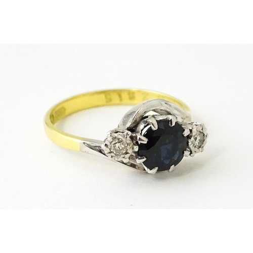 622 - An 18ct gold ring with platinum set central sapphire flanked by diamonds. Ring size approx. N