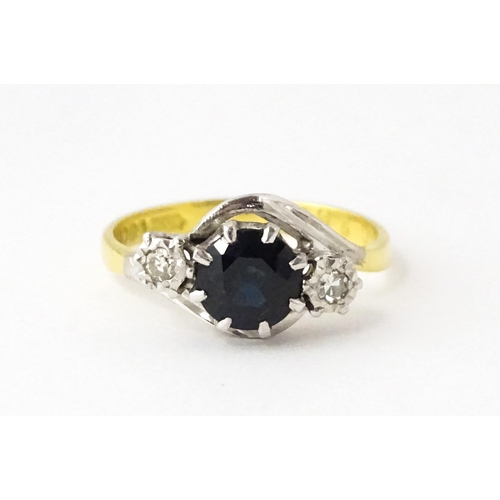 622 - An 18ct gold ring with platinum set central sapphire flanked by diamonds. Ring size approx. N