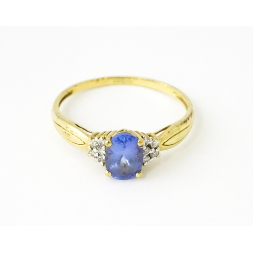 624 - A 9ct gold ring set with central tanzanite flanked by diamonds. Ring size approx. S