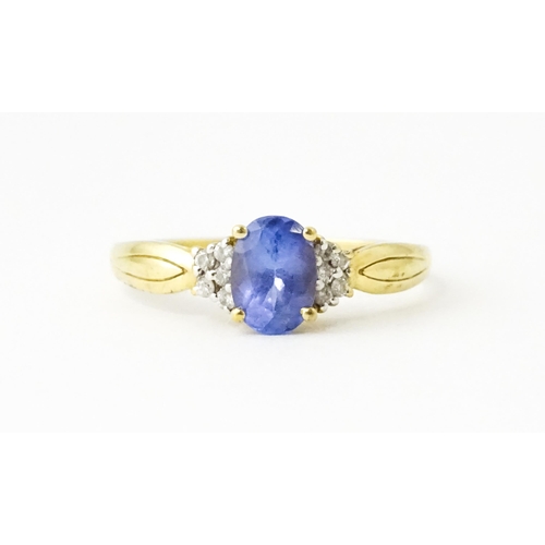 624 - A 9ct gold ring set with central tanzanite flanked by diamonds. Ring size approx. S