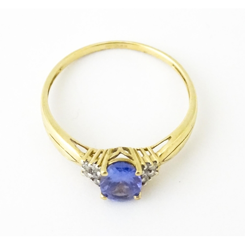 624 - A 9ct gold ring set with central tanzanite flanked by diamonds. Ring size approx. S