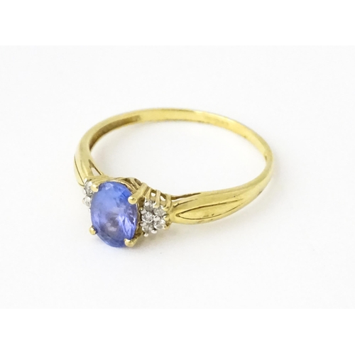 624 - A 9ct gold ring set with central tanzanite flanked by diamonds. Ring size approx. S