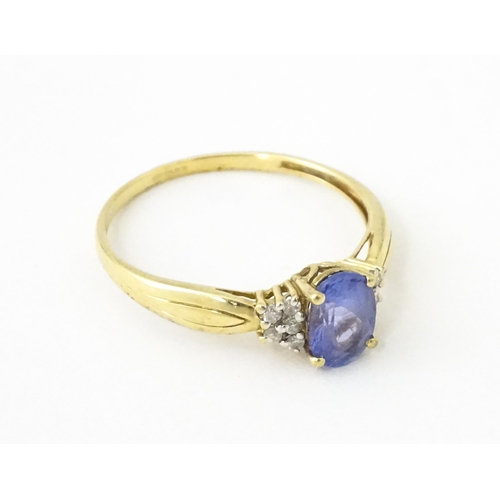 624 - A 9ct gold ring set with central tanzanite flanked by diamonds. Ring size approx. S