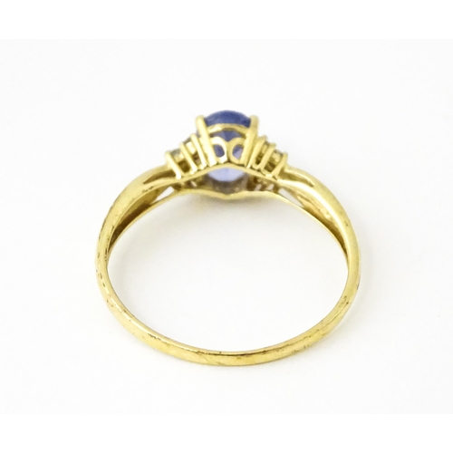 624 - A 9ct gold ring set with central tanzanite flanked by diamonds. Ring size approx. S