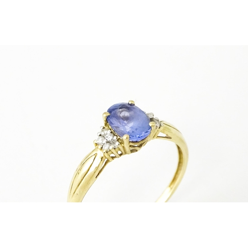 624 - A 9ct gold ring set with central tanzanite flanked by diamonds. Ring size approx. S