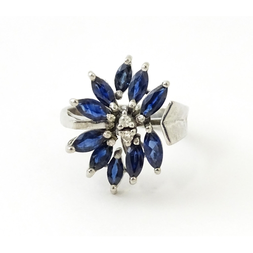 636 - A white metal dress ring set with a profusion of sapphires and two central diamonds in a stylised fl... 