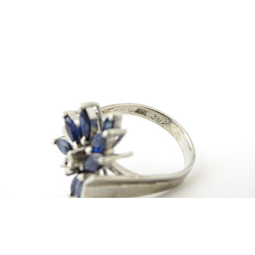 636 - A white metal dress ring set with a profusion of sapphires and two central diamonds in a stylised fl... 