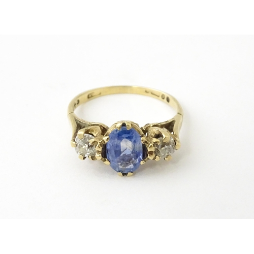 637 - A 14ct gold ring set with central sapphire flanked by diamonds. Ring size approx. J 1/2