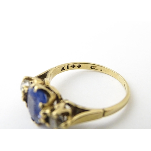 637 - A 14ct gold ring set with central sapphire flanked by diamonds. Ring size approx. J 1/2