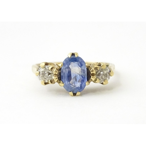 637 - A 14ct gold ring set with central sapphire flanked by diamonds. Ring size approx. J 1/2