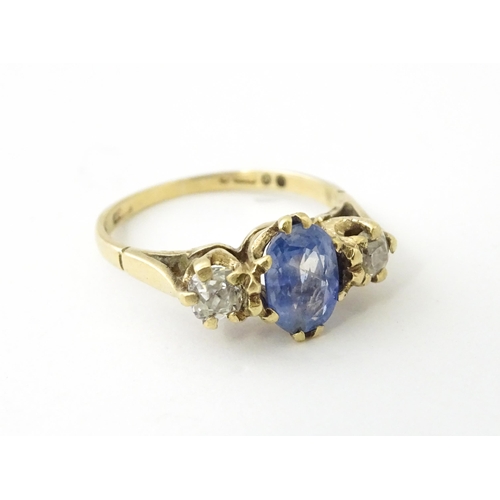 637 - A 14ct gold ring set with central sapphire flanked by diamonds. Ring size approx. J 1/2