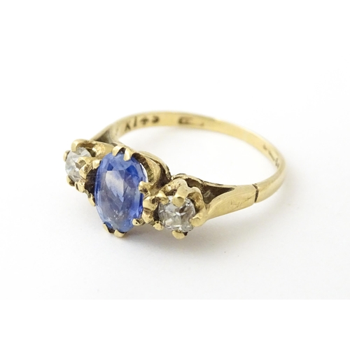 637 - A 14ct gold ring set with central sapphire flanked by diamonds. Ring size approx. J 1/2