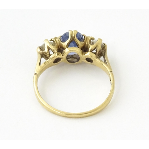 637 - A 14ct gold ring set with central sapphire flanked by diamonds. Ring size approx. J 1/2