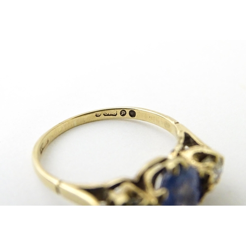 637 - A 14ct gold ring set with central sapphire flanked by diamonds. Ring size approx. J 1/2