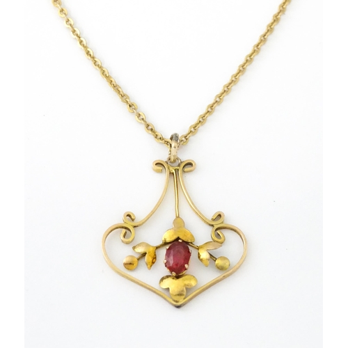 639 - An Art Nouveau yellow metal necklace, the pendant set with red stone detail. Pendant approx. 1 1/4