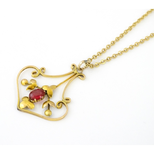 639 - An Art Nouveau yellow metal necklace, the pendant set with red stone detail. Pendant approx. 1 1/4