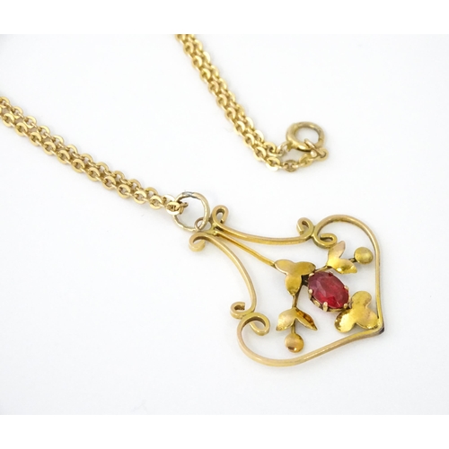 639 - An Art Nouveau yellow metal necklace, the pendant set with red stone detail. Pendant approx. 1 1/4