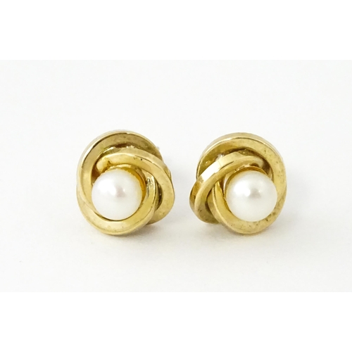 642 - A pair of 9ct gold stud earrings set with central pearl within a twist setting.