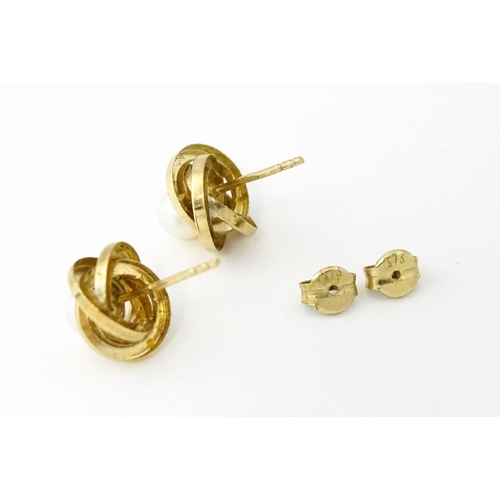 642 - A pair of 9ct gold stud earrings set with central pearl within a twist setting.