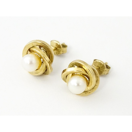 642 - A pair of 9ct gold stud earrings set with central pearl within a twist setting.