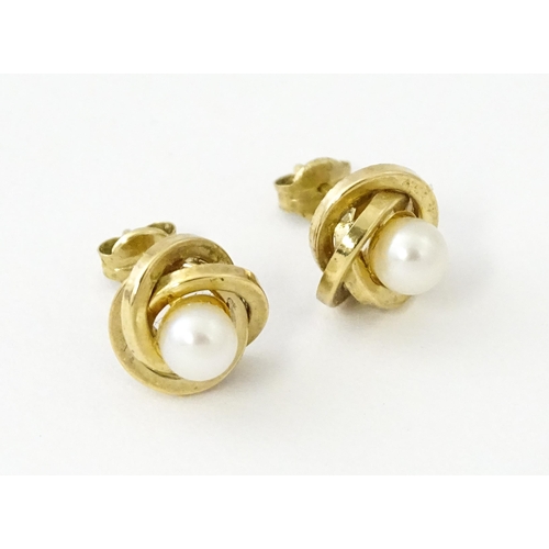 642 - A pair of 9ct gold stud earrings set with central pearl within a twist setting.