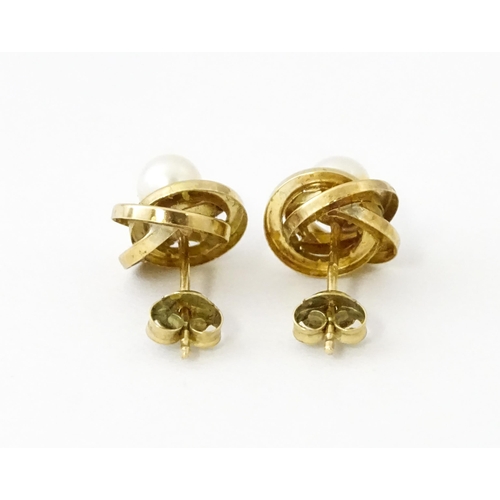 642 - A pair of 9ct gold stud earrings set with central pearl within a twist setting.