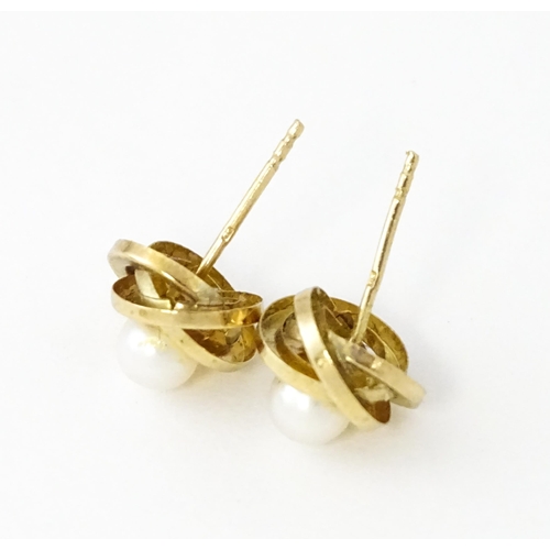 642 - A pair of 9ct gold stud earrings set with central pearl within a twist setting.