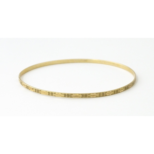 645 - A 9ct gold bracelet of bangle form with engraved decoration. Approx. 2 3/4