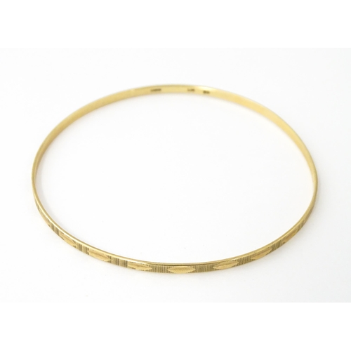 645 - A 9ct gold bracelet of bangle form with engraved decoration. Approx. 2 3/4