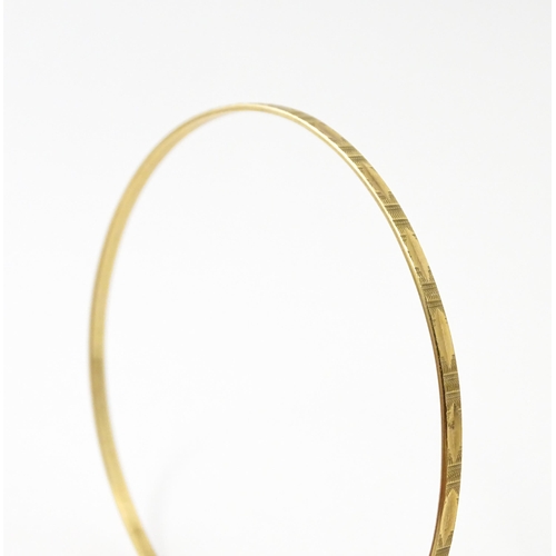 645 - A 9ct gold bracelet of bangle form with engraved decoration. Approx. 2 3/4