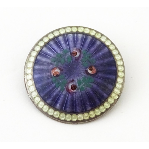 652 - A silver brooch of circular form with purple guilloche enamel decoration and floral detail, hallmark... 