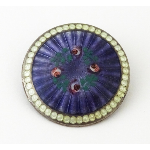 652 - A silver brooch of circular form with purple guilloche enamel decoration and floral detail, hallmark... 