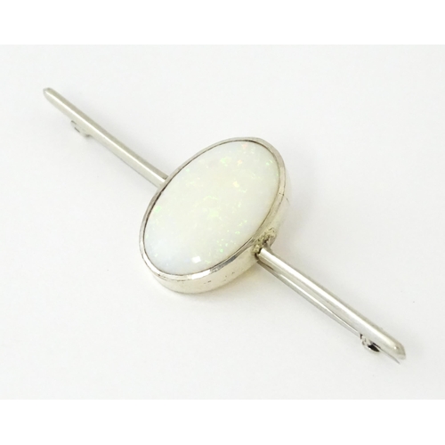 662 - A 9ct white gold bar brooch set with central oval opal cabochon. The opal approx. 3/4