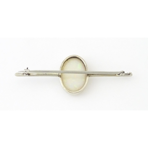 662 - A 9ct white gold bar brooch set with central oval opal cabochon. The opal approx. 3/4