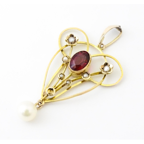 664 - A 9ct gold pendant in the Art Nouveau style set with central garnet flanked by seed pearls with pear... 